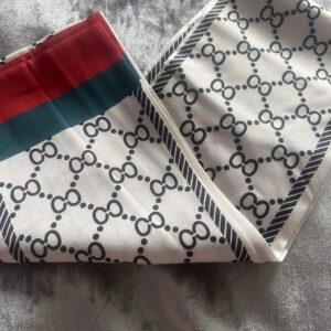 Close-up of Gucci-patterned fabric with red and green stripes.